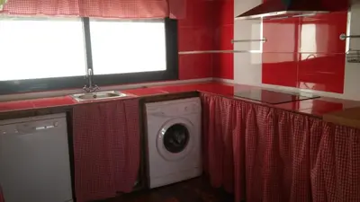 a washing machine in a kitchen with red walls at Casa Amelie in Hozanejos