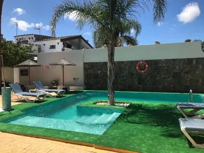 a swimming pool with a palm tree next to a house at Casa Amelie in Hozanejos