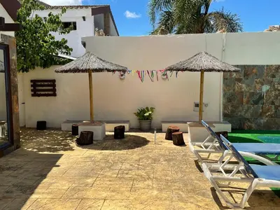 a patio with two umbrellas and a swimming pool at Casa Amelie in Hozanejos