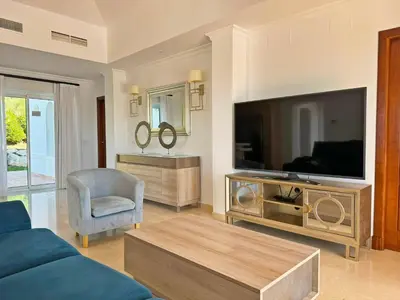 a living room with a large television and a blue couch at Villa Los Olivos - Ole Solutions in Arcos de la Frontera