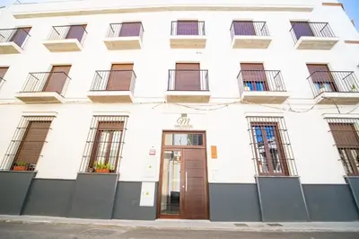 a white building with a brown door and windows at Piso Torno in Sanlúcar de Barrameda