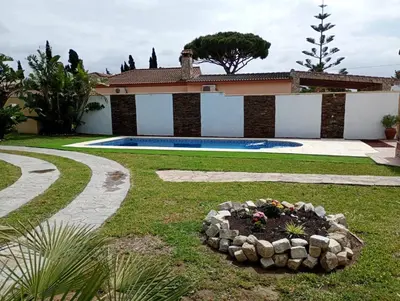 a backyard with a swimming pool and a garden with a flower bed at Chalet Pura Vida in Chiclana de la Frontera