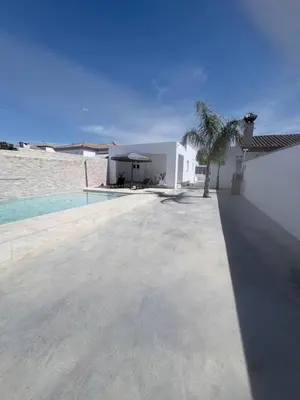 a swimming pool with blue water in front of a house at Erika & Julia in Chiclana de la Frontera