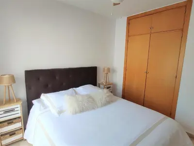 a bedroom with a large white bed with a wooden cabinet at Villa Libertad in Conil de la Frontera