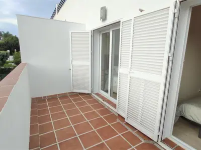 a balcony with white shutters and a tile floor at Villa Libertad in Conil de la Frontera