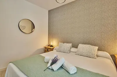 a bedroom with a bed with two pillows and a mirror at Redo Home in Cádiz