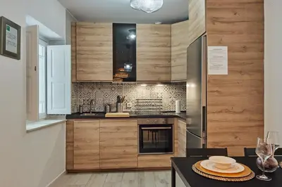 a kitchen with wooden cabinets and a table with plates at Redo Home in Cádiz