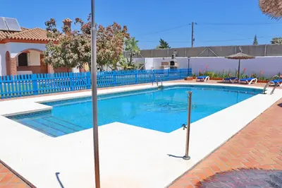 a large swimming pool with a blue fence at Chalet La Florida in Conil de la Frontera