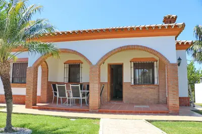a house with a patio with a palm tree at Chalet La Florida in Conil de la Frontera