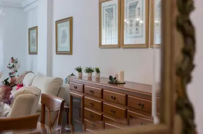 a living room with a dresser and two chairs at Avenida Playa 3 Rooms 2 baños in Cádiz