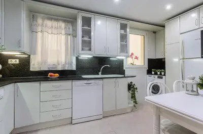 a kitchen with white cabinets and a sink at Avenida Playa 3 Rooms 2 baños in Cádiz