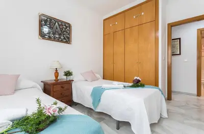 a hotel room with two beds and a dresser at Avenida Playa 3 Rooms 2 baños in Cádiz