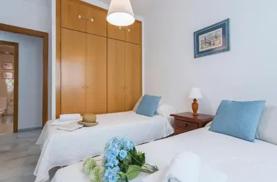 a bedroom with two beds and a wooden cabinet at Avenida Playa 3 Rooms 2 baños in Cádiz
