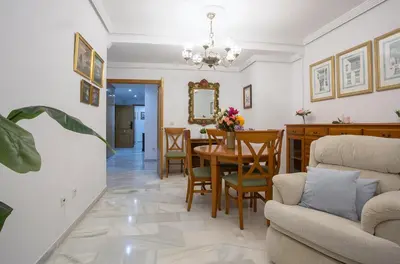a dining room and living room with a table and chairs at Avenida Playa 3 Rooms 2 baños in Cádiz