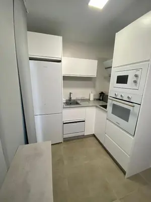 a white kitchen with white appliances and a tile floor at Loft Deluxe Raquel in Conil de la Frontera