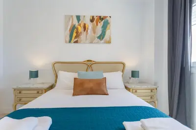 a bedroom with a white bed with a blue blanket at ACQUARELA Family Home free parking by Cadiz4Rentals in Cádiz