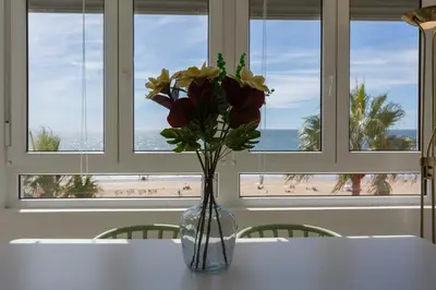 a vase of flowers sitting on a table with a view of the beach at ACQUARELA Family Home free parking by Cadiz4Rentals in Cádiz