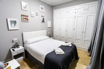 a small bedroom with a bed and white cabinets at SH Lupe Caleta Beach. A 100 m de playa in Cádiz