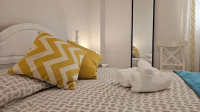 a white bedroom with a bed with yellow pillows at CASA BLANCA-Parking gratis in Sanlúcar de Barrameda