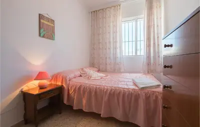 a small bedroom with a bed and a table with a lamp at 6 Bedroom Gorgeous Home In Chipiona in Chipiona