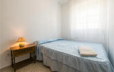 a bedroom with a bed and a table with a lamp at 6 Bedroom Gorgeous Home In Chipiona in Chipiona