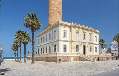 a large brick building with a chimney and palm trees at 6 Bedroom Gorgeous Home In Chipiona in Chipiona