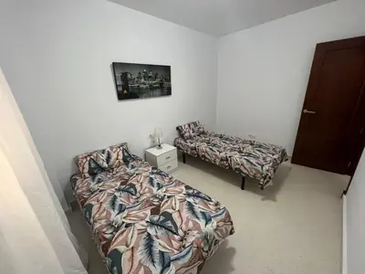 a bedroom with two beds and a nightstand and a bed and a bedskirts at Esteros de San Fernando in San Fernando