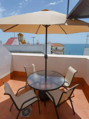 a table with chairs and an umbrella on a balcony at Atico del Buen CANTAOR by Cadiz4Rentals in Cádiz