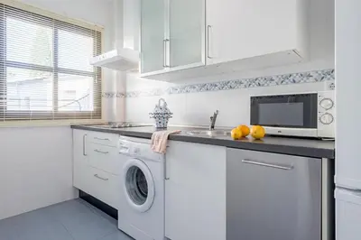 a white kitchen with a washing machine and a microwave at Jerez Paralejo Ha Apartment in Jerez de la Frontera