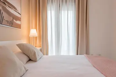 a bedroom with a large white bed with a window at Jerez Paralejo Ha Apartment in Jerez de la Frontera