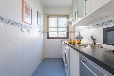 a white kitchen with a sink and a counter at Jerez Paralejo Ha Apartment in Jerez de la Frontera