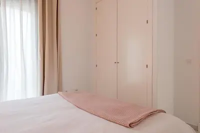 a bed with a pink blanket on top of it at Jerez Paralejo Ha Apartment in Jerez de la Frontera