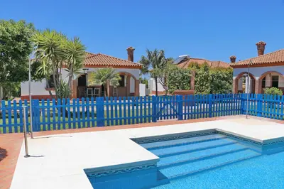 a blue fence with a pool in front of a house at Chalet Florida II in Conil de la Frontera