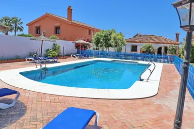 a swimming pool with chairs and a house at Chalet Florida II in Conil de la Frontera