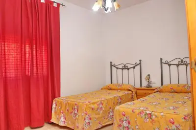 a bedroom with two beds and red curtains at Chalet Florida II in Conil de la Frontera