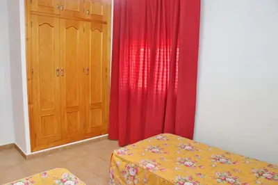 a room with a red curtain and a bed and a door at Chalet Florida II in Conil de la Frontera