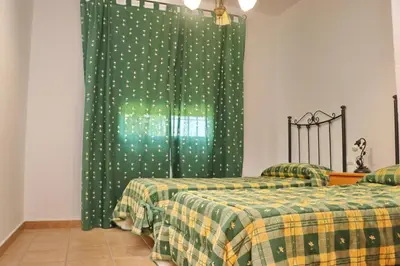 a bedroom with two beds and a green curtain at Chalet Florida II in Conil de la Frontera