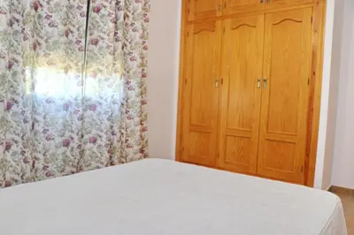 a bedroom with a bed and a wooden cabinet at Chalet Florida II in Conil de la Frontera