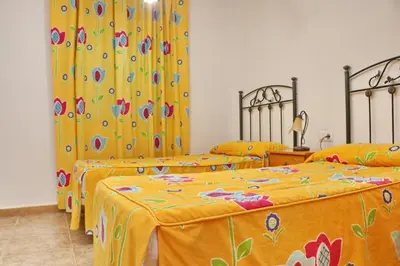 two beds in a room with yellow and colorful sheets at Chalet Florida IV in Conil de la Frontera