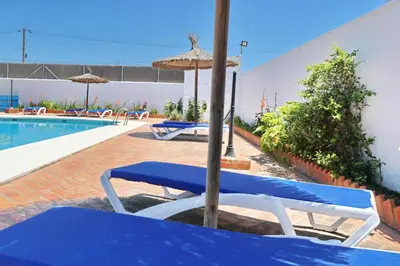 a pool with blue and white chairs and an umbrella at Chalet Florida IV in Conil de la Frontera