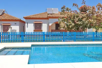 a house with a blue fence and a swimming pool at Chalet Florida IV in Conil de la Frontera