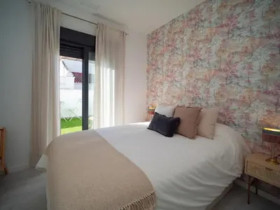 a bedroom with a white bed with a floral wall at El ático de Reyes in Sanlúcar de Barrameda