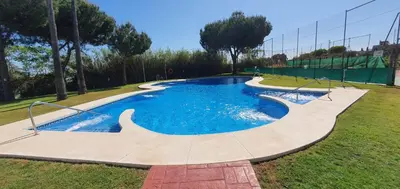 a swimming pool in a park with blue water at Apartamento turístico la jara in Sanlúcar de Barrameda