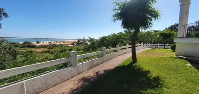a white fence with a tree next to a sidewalk at Apartamento turístico la jara in Sanlúcar de Barrameda