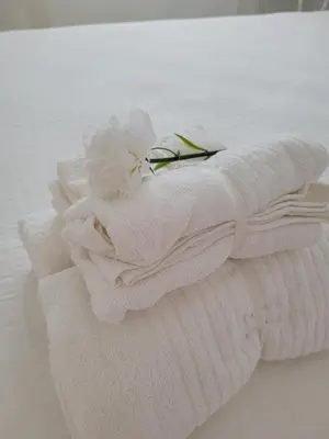 a stack of white towels with a flower on top at La Costilla centro y playa in Rota