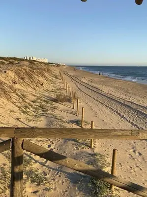 a wooden fence on a beach near the ocean at La Costilla centro y playa in Rota