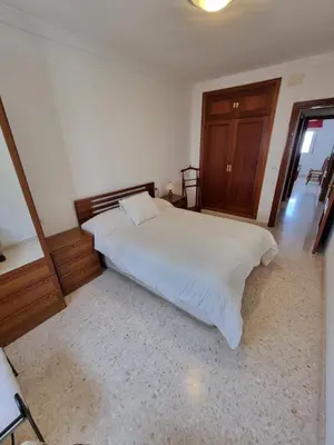 a kitchen with white cabinets and a table and a chair at Gallegos House in Lebrija