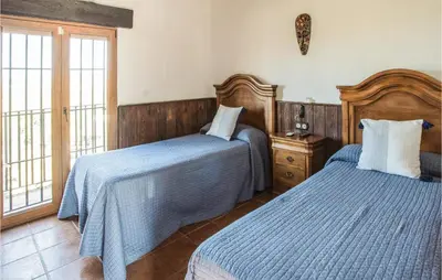 a bedroom with two beds with blue comforters at Amazing Home In Arcos De La Frontera in Arcos de la Frontera