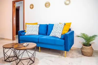 a blue couch in a living room with a table at Apartamento AGUAMAR in Sanlúcar de Barrameda