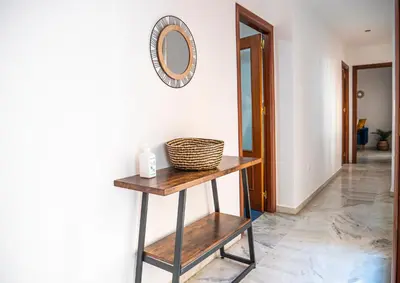 a shelf with a mirror and a basket on a wall at Apartamento AGUAMAR in Sanlúcar de Barrameda
